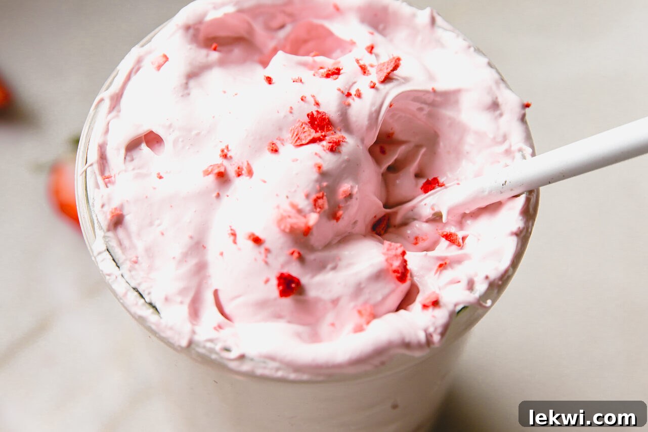 A spoon dipping into a jar of strawberry marshmallow fluff.