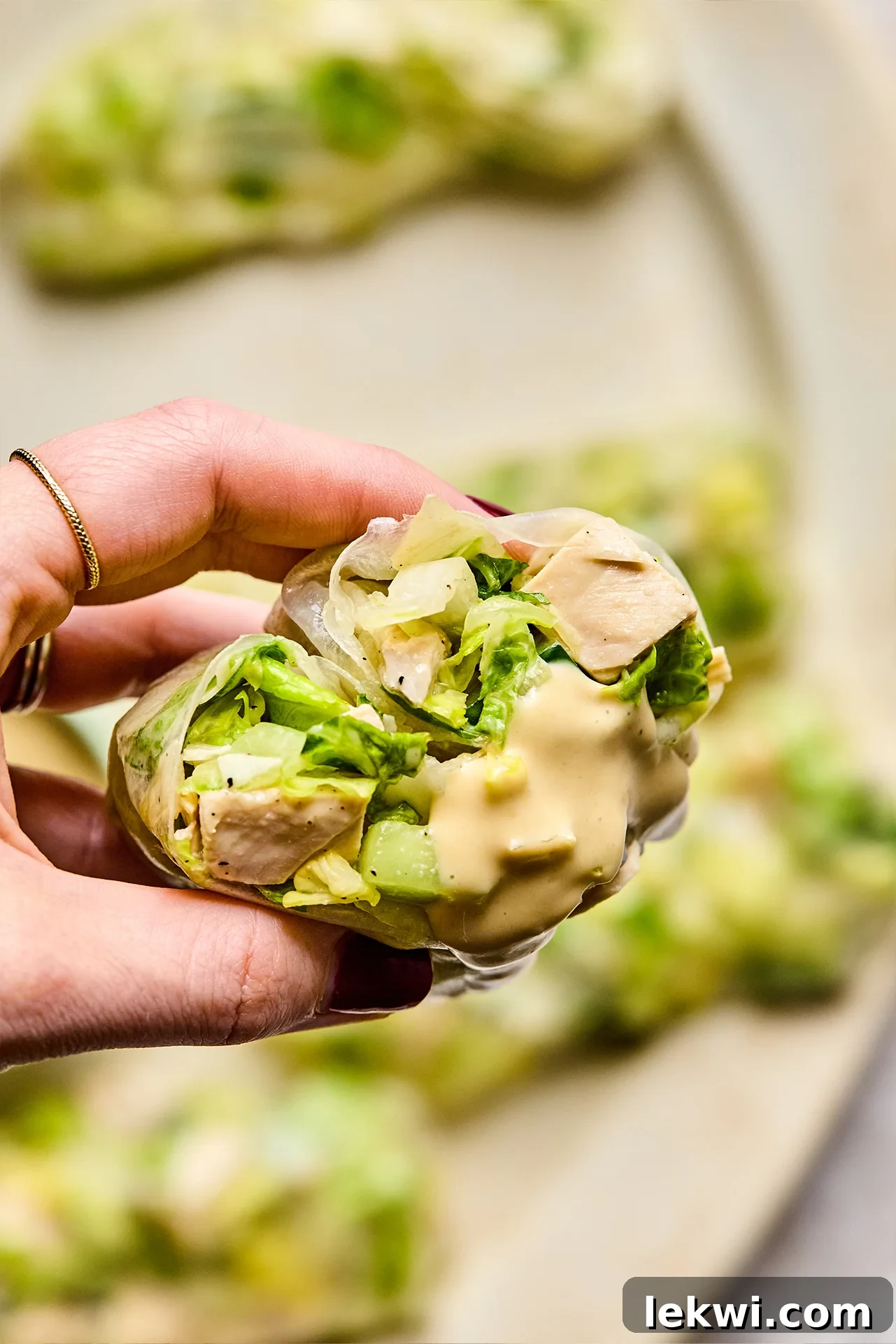 Caesar rice paper roll cut in half with some dressing, highlighting the fresh filling.