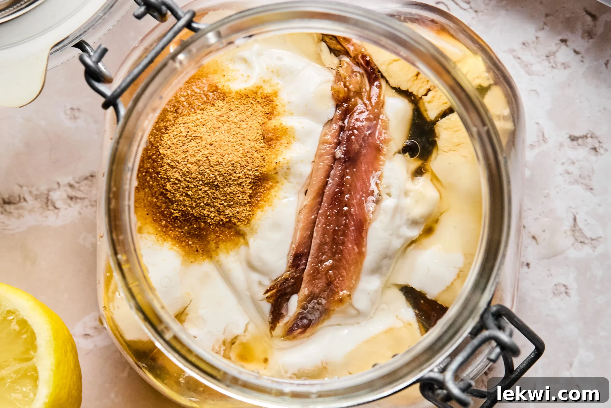 All the ingredients for the homemade dairy-free Caesar dressing combined in a wide-mouth jar, perfectly ready for blending.