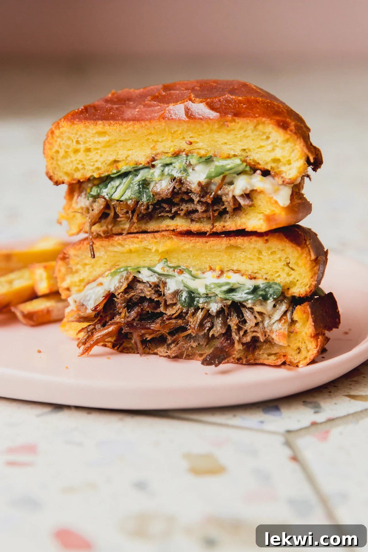 Pot roast sandwich sliced in half and stacked, showcasing tender meat and melted cheese.