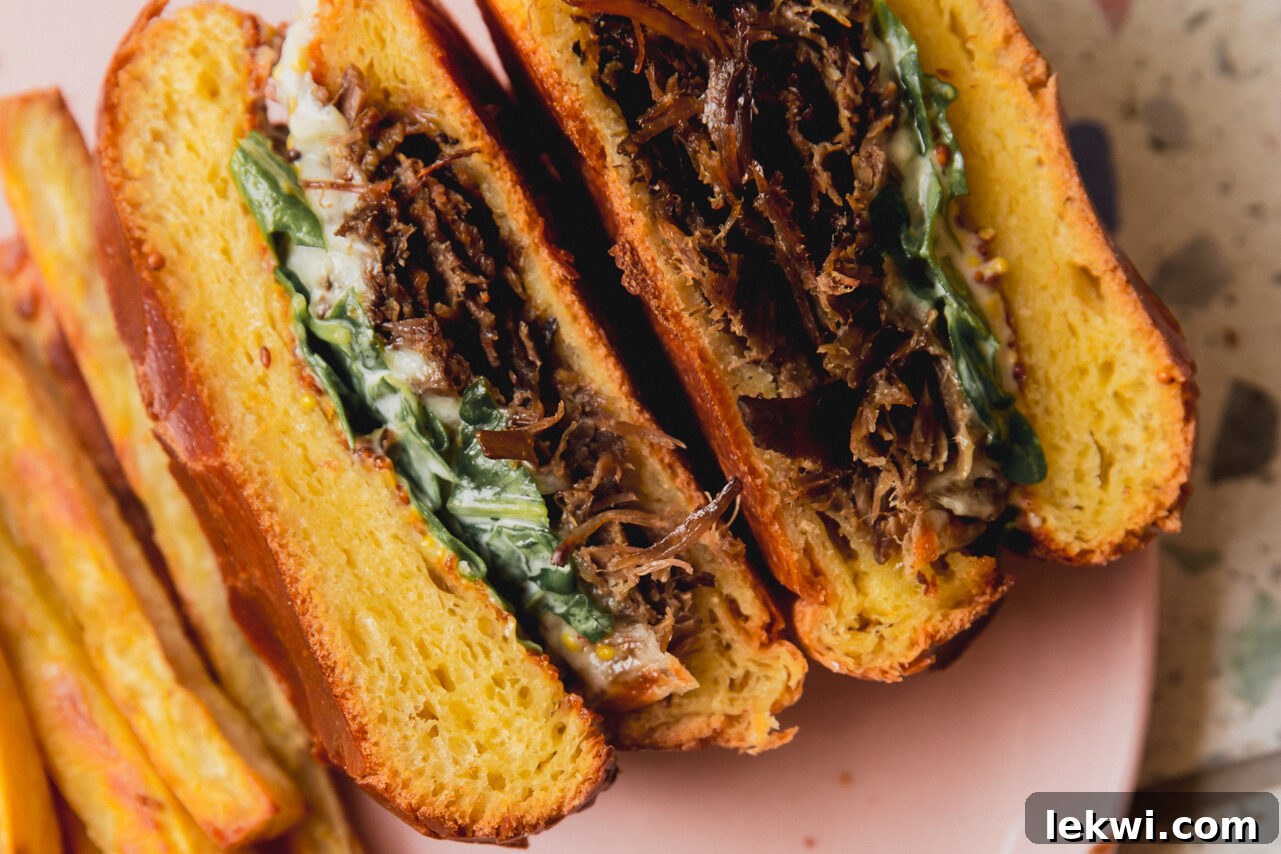 A finished slow cooker pot roast sandwich, perfectly cut in half and ready to serve.