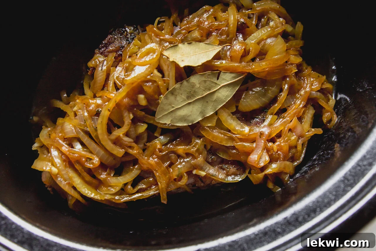 Slow cooker pot roast topped with a mixture of caramelized onions and bay leaves.