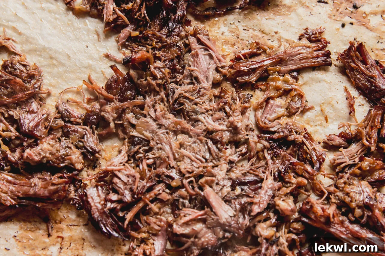 Shredded slow cooker pot roast spread on a baking sheet, ready for a light crisp.