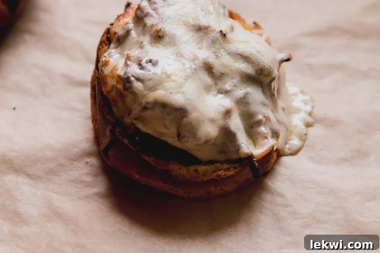 Open-faced pot roast sandwich with melted provolone cheese on a baking sheet.