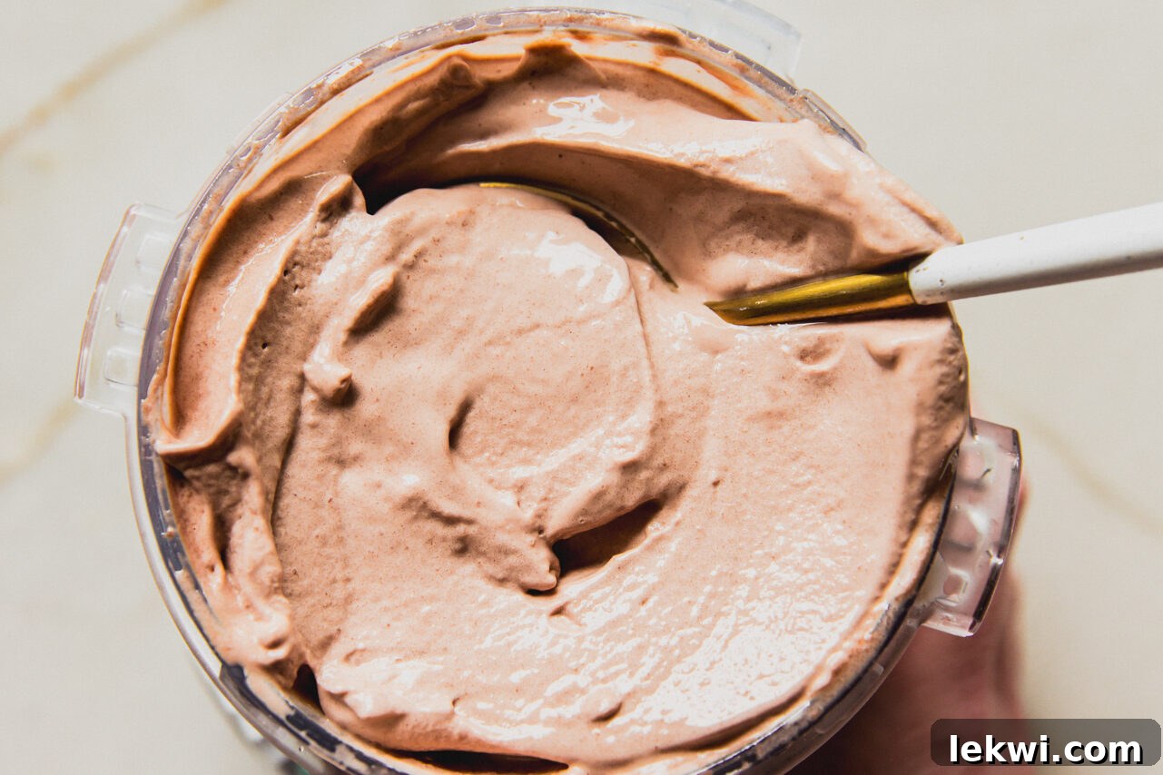 Chocolate protein ice cream fully prepared in a ninja creami container with a spoon, ready to be served.