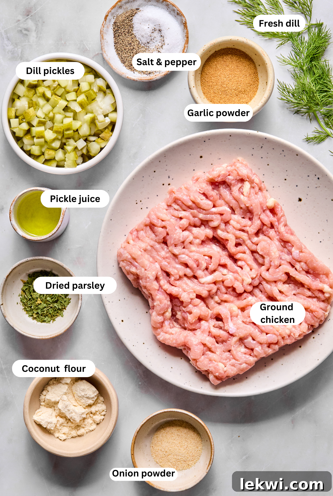 A selection of fresh ingredients including ground chicken, dill pickles, herbs, and spices laid out before making pickle chicken burgers.
