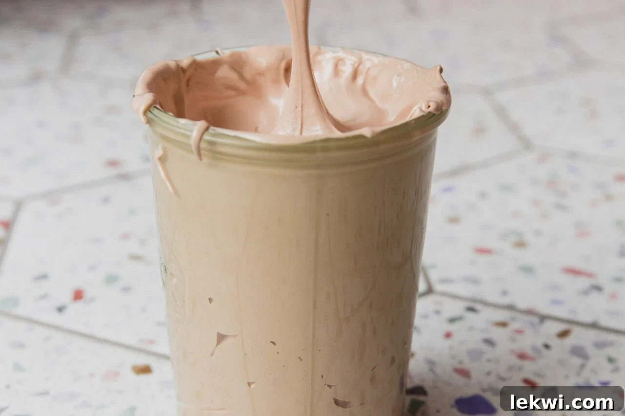 Marshmallow fluff being put into a glass container. 