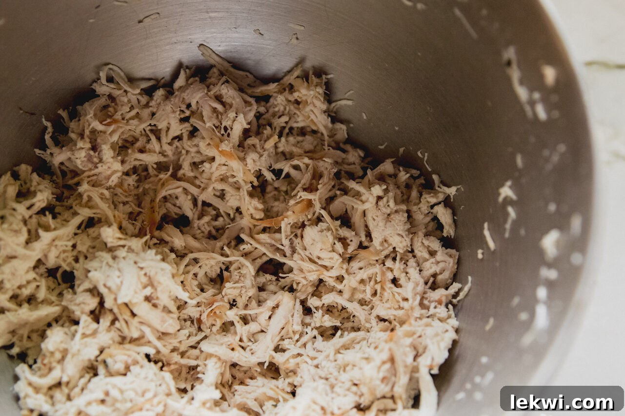 A mixing bowl filled with perfectly shredded chicken, ready for the next steps.