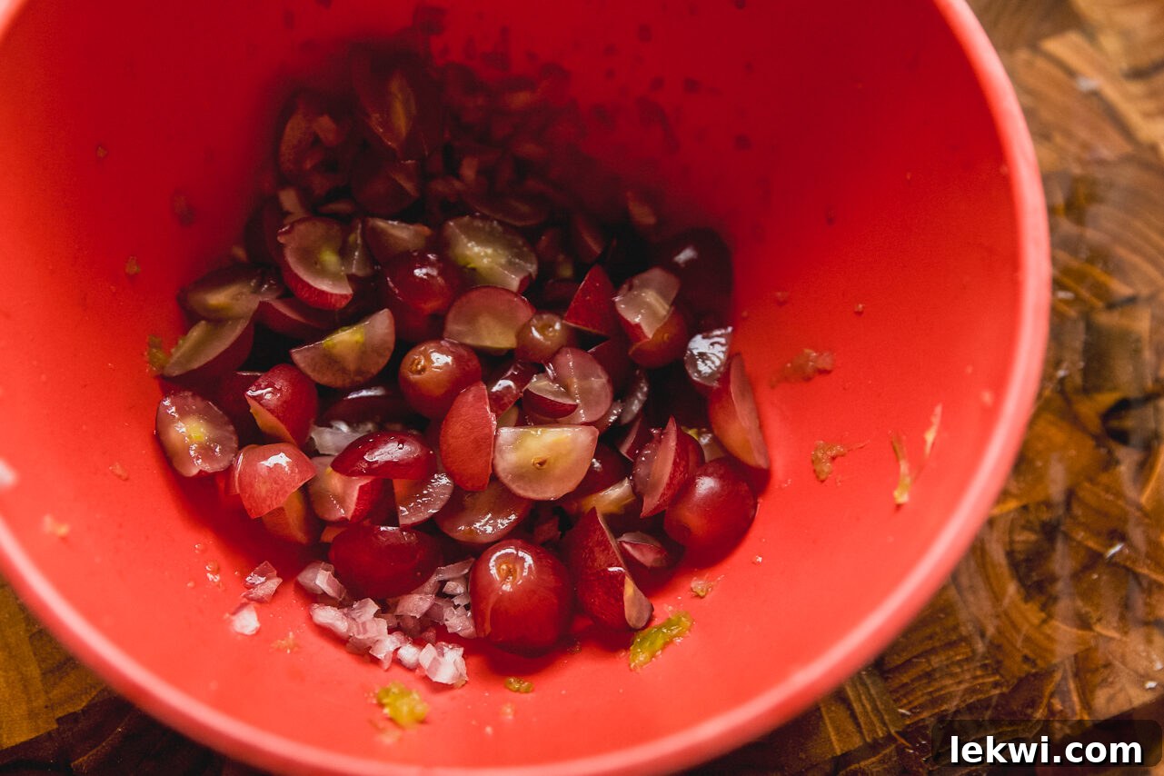 A bowl containing finely chopped grapes, celery, and shallots, showing the prepped fresh ingredients.