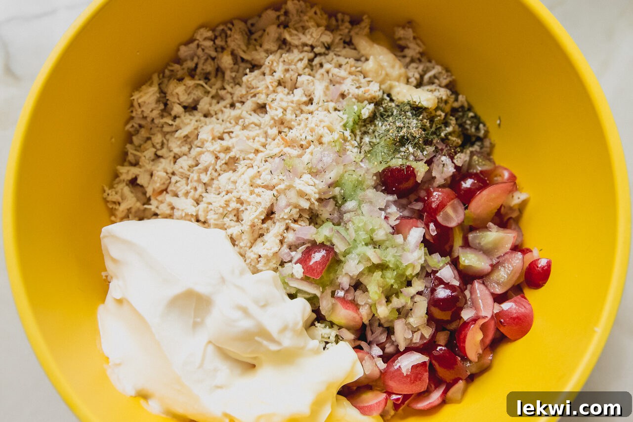 All the ingredients for the chicken salad in a bowl before mixing, with the dressing components on top.