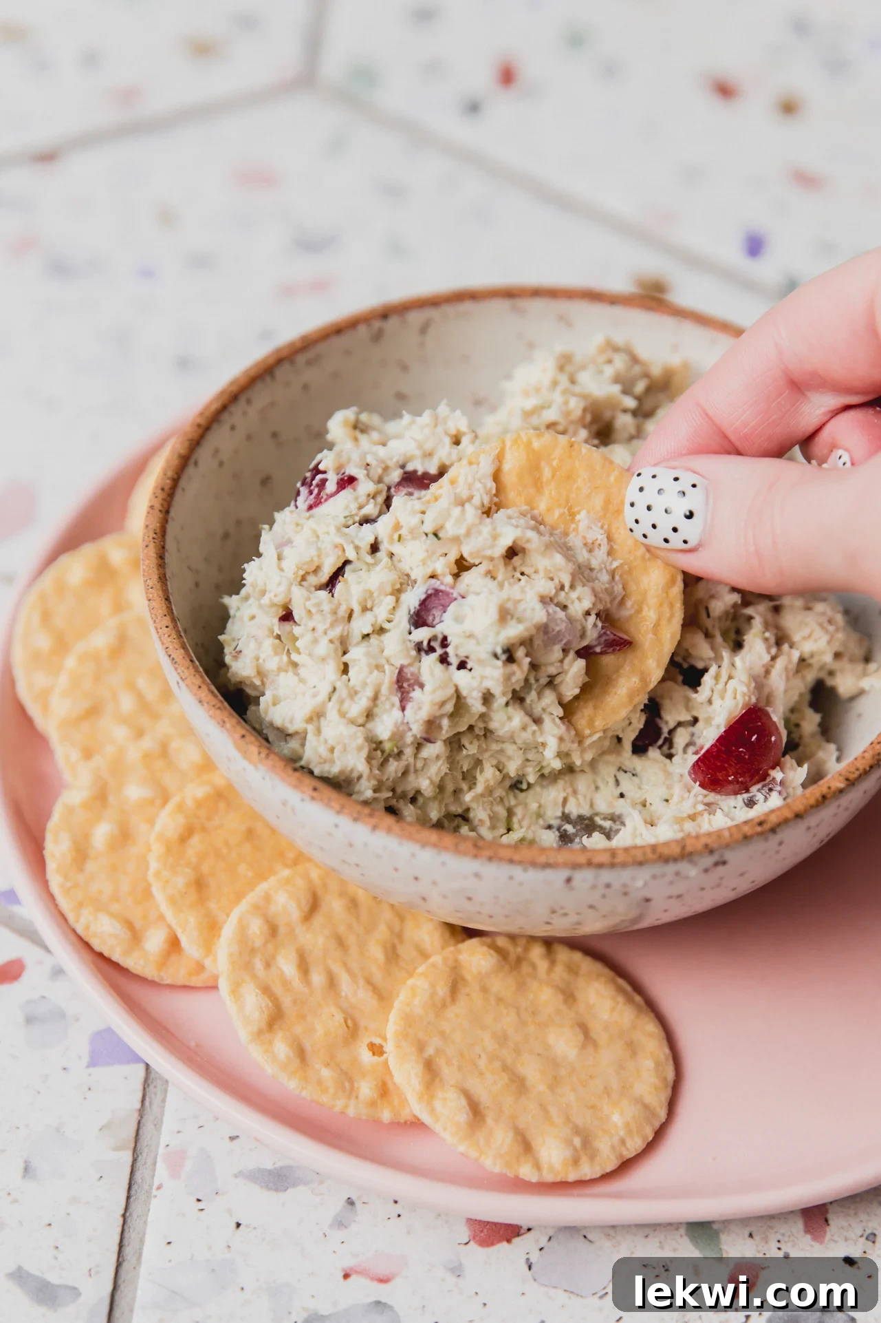 Creamy grape chicken salad in a serving bowl with a cracker, ready to eat.