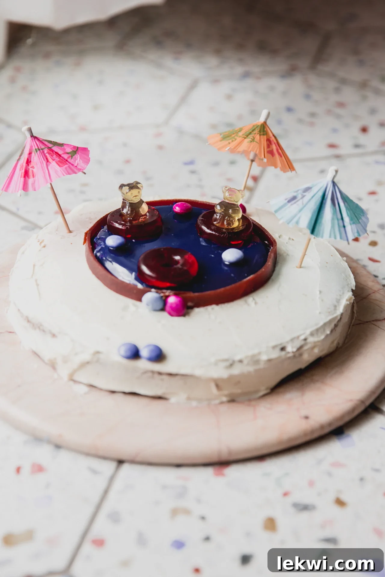 Vibrant swimming pool cake adorned with miniature paper umbrellas, perfect for a summer party.