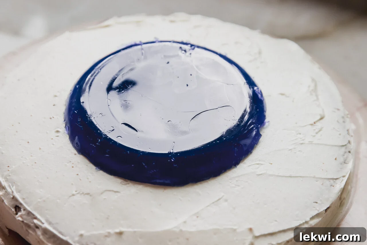 A perfectly set jello pool being carefully placed onto a frosted cake.