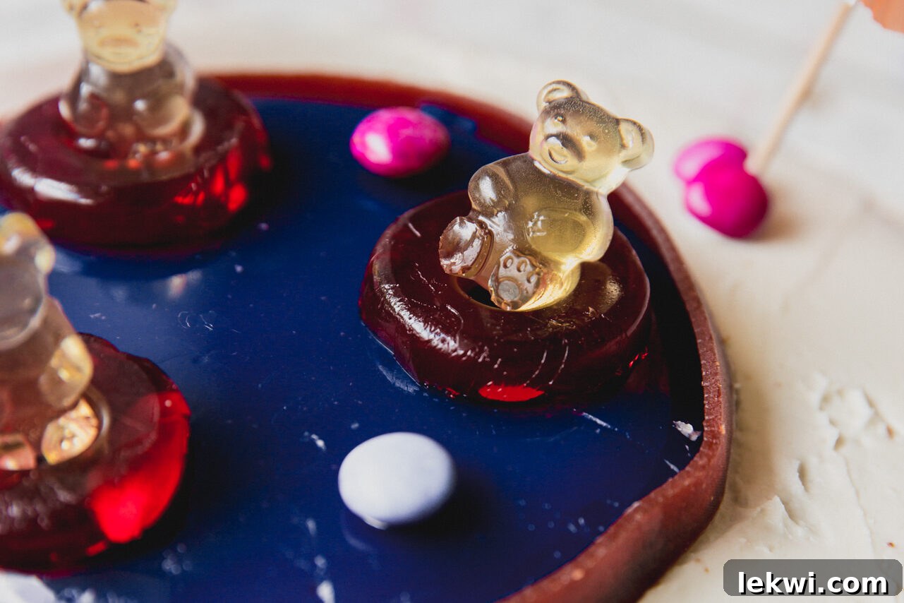 The fully decorated swimming pool cake, featuring gummy bears in ring floaties and paper umbrellas.