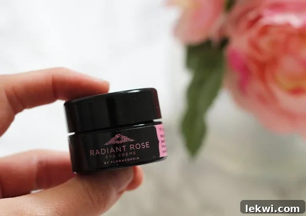 A hand holding a small container of radiant rose .