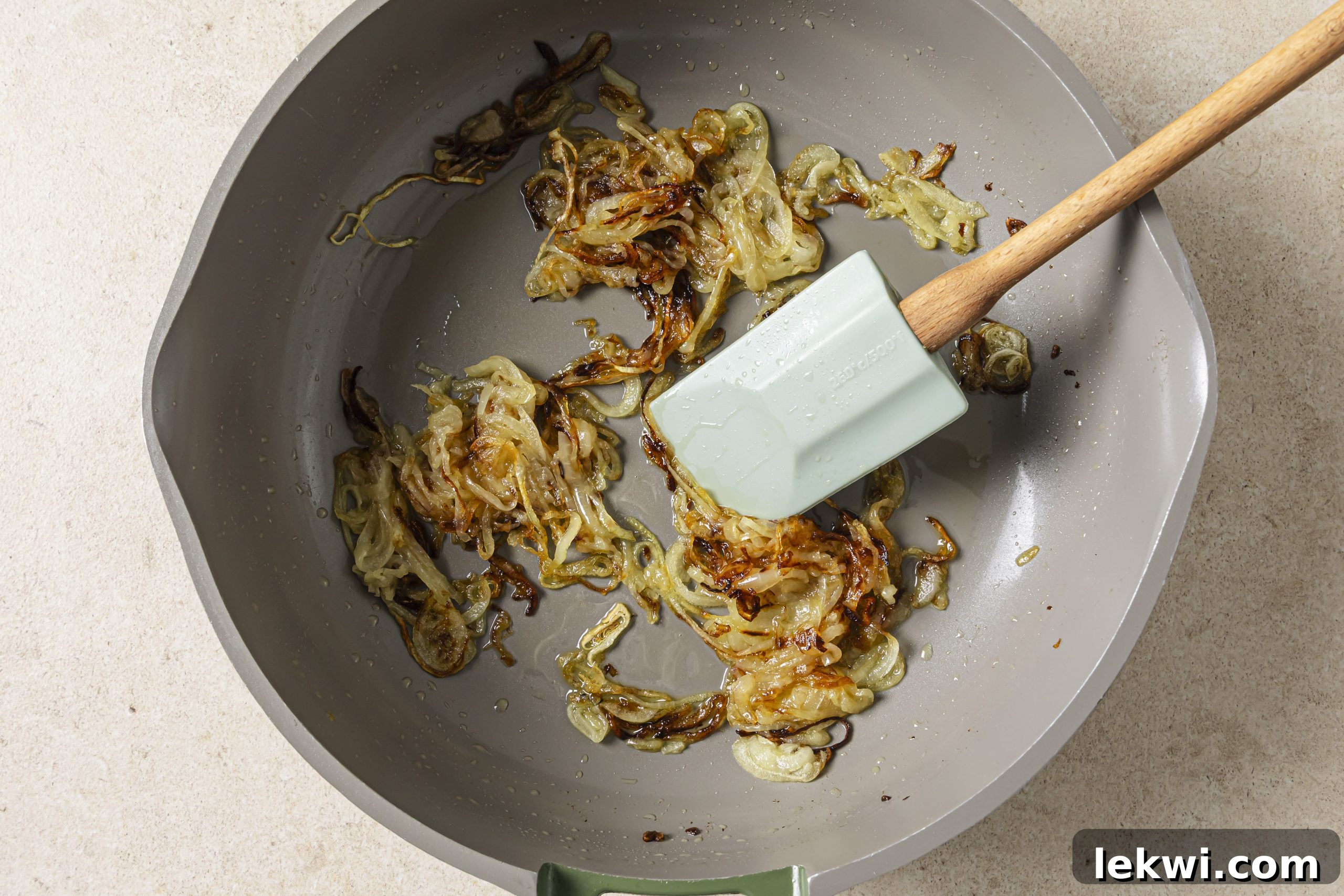 Sliced yellow onions caramelizing to a golden brown in a pan with ghee.