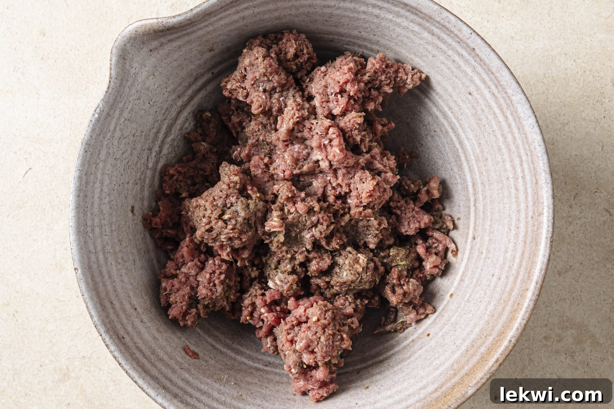 Ground beef being mixed with various spices in a bowl, preparing for smashburger tacos.