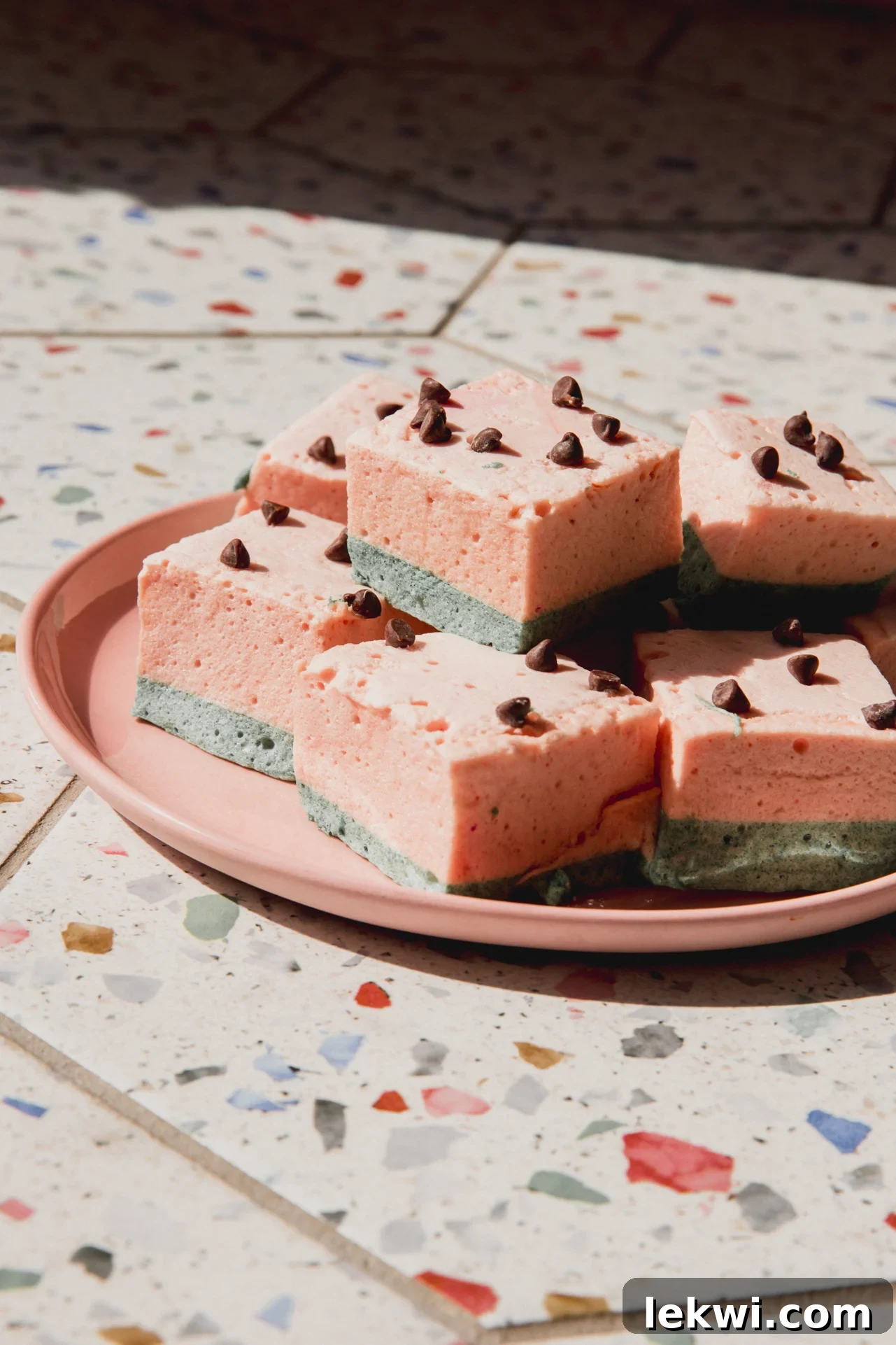 Watermelon marshmallows stacked on a pink plate.