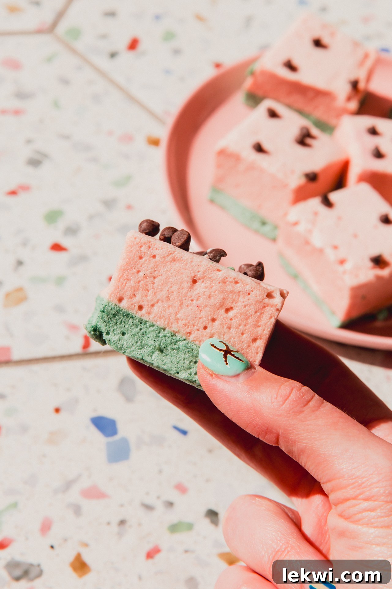 A hand holding one watermelon marshmallow before eating.
