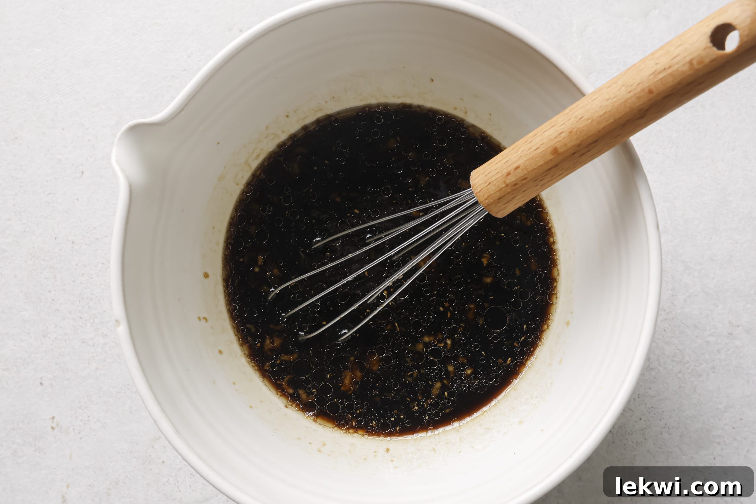 All the sauce ingredients being whisked together in a mixing bowl until thoroughly combined.