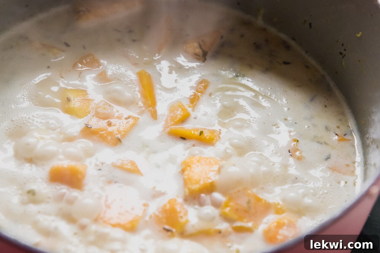 Butternut squash, shallots, and garlic simmering in a rich blend of coconut milk and chicken broth in a Dutch oven, slowly softening.