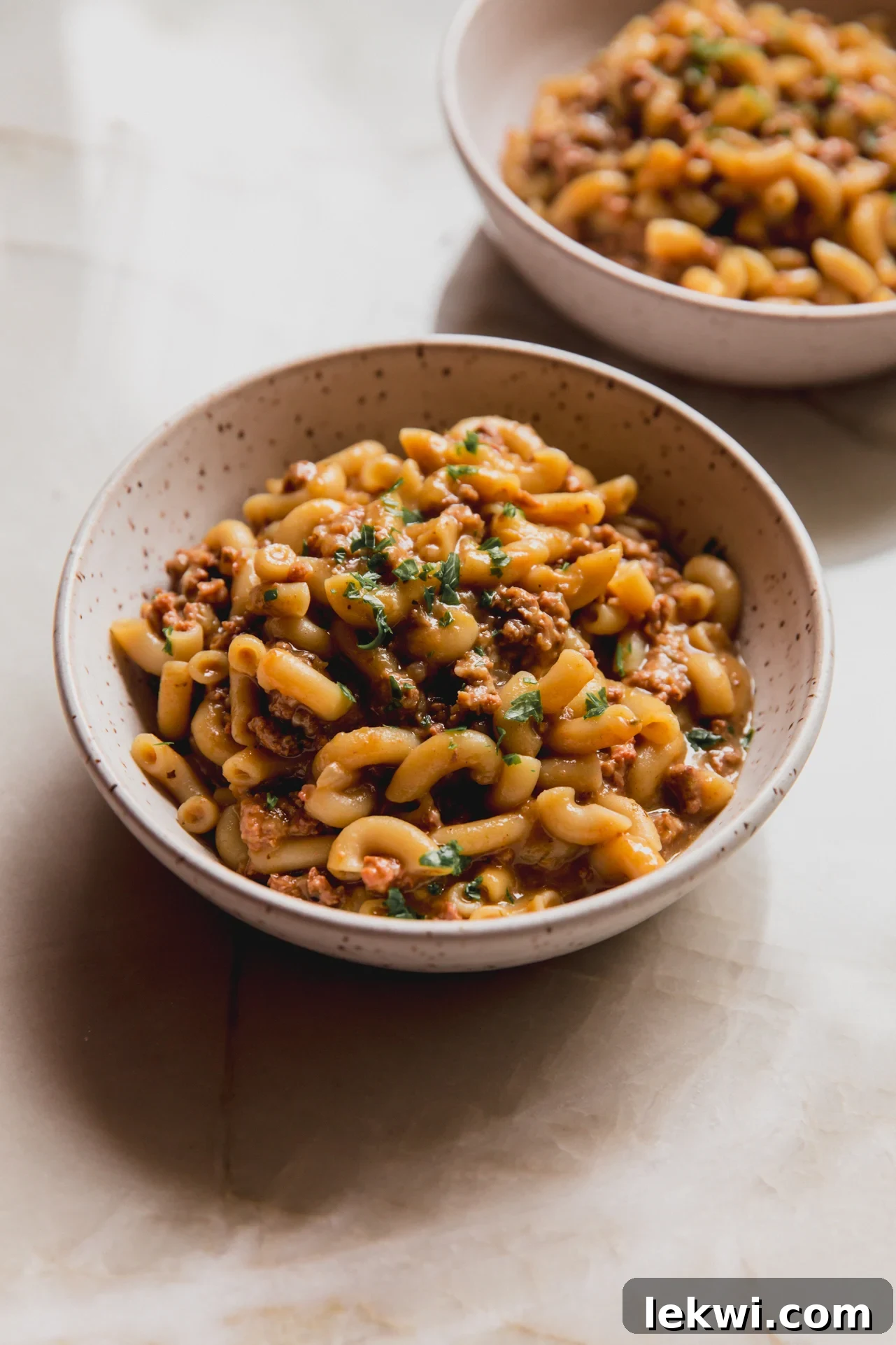 Slow cooker hamburger helper in a bowl topped with parsley.