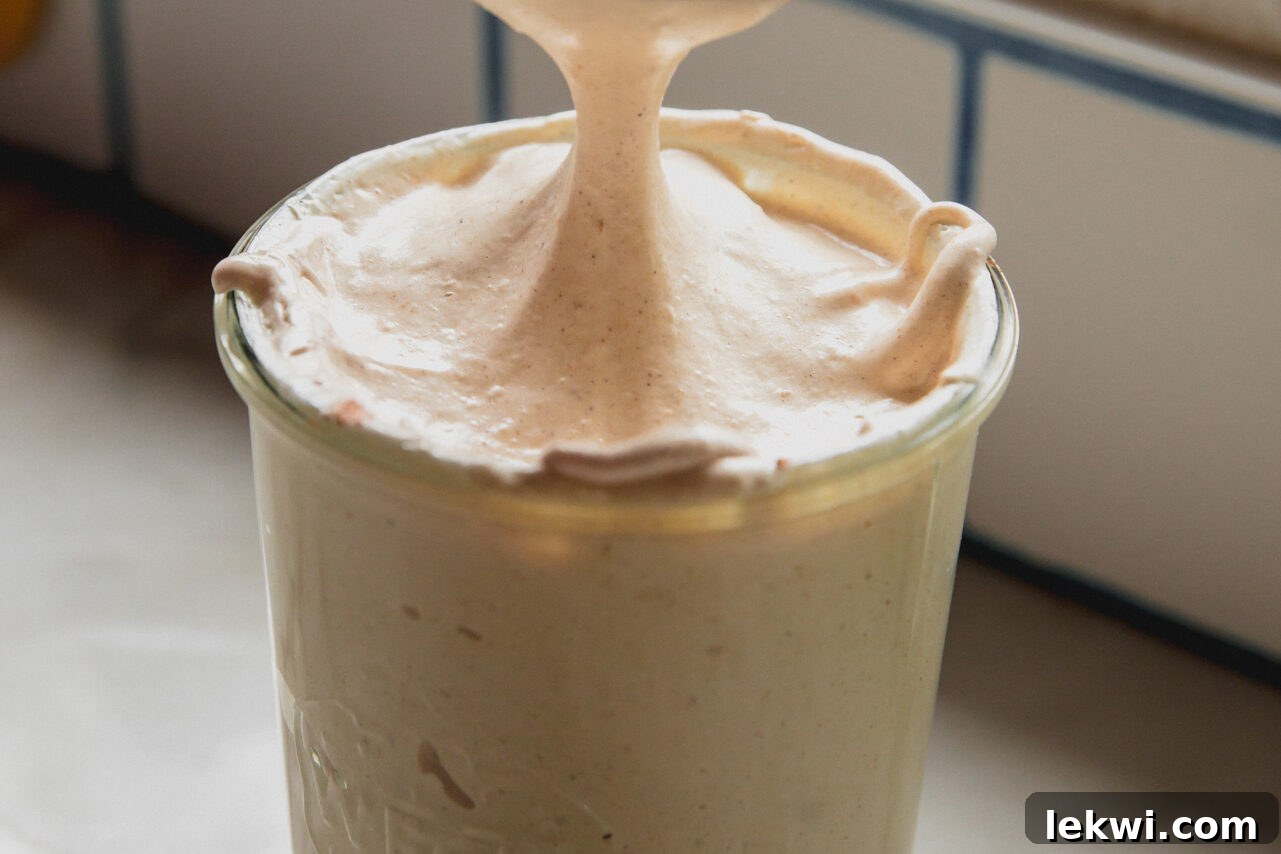 Pumpkin spice marshmallow fluff with a spoon scooping some of the fluff. 