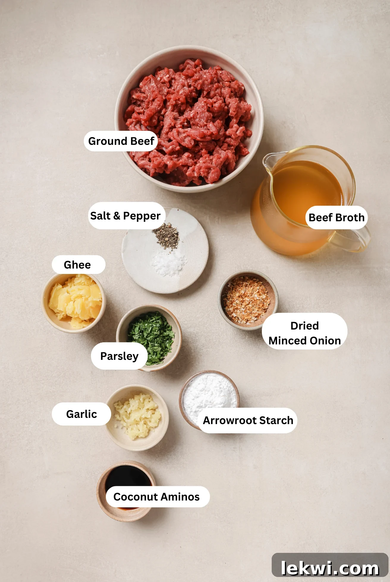 All the fresh and pantry ingredients laid out for making the ground beef and gravy recipe, including ground beef, beef broth, arrowroot starch, and aromatics.