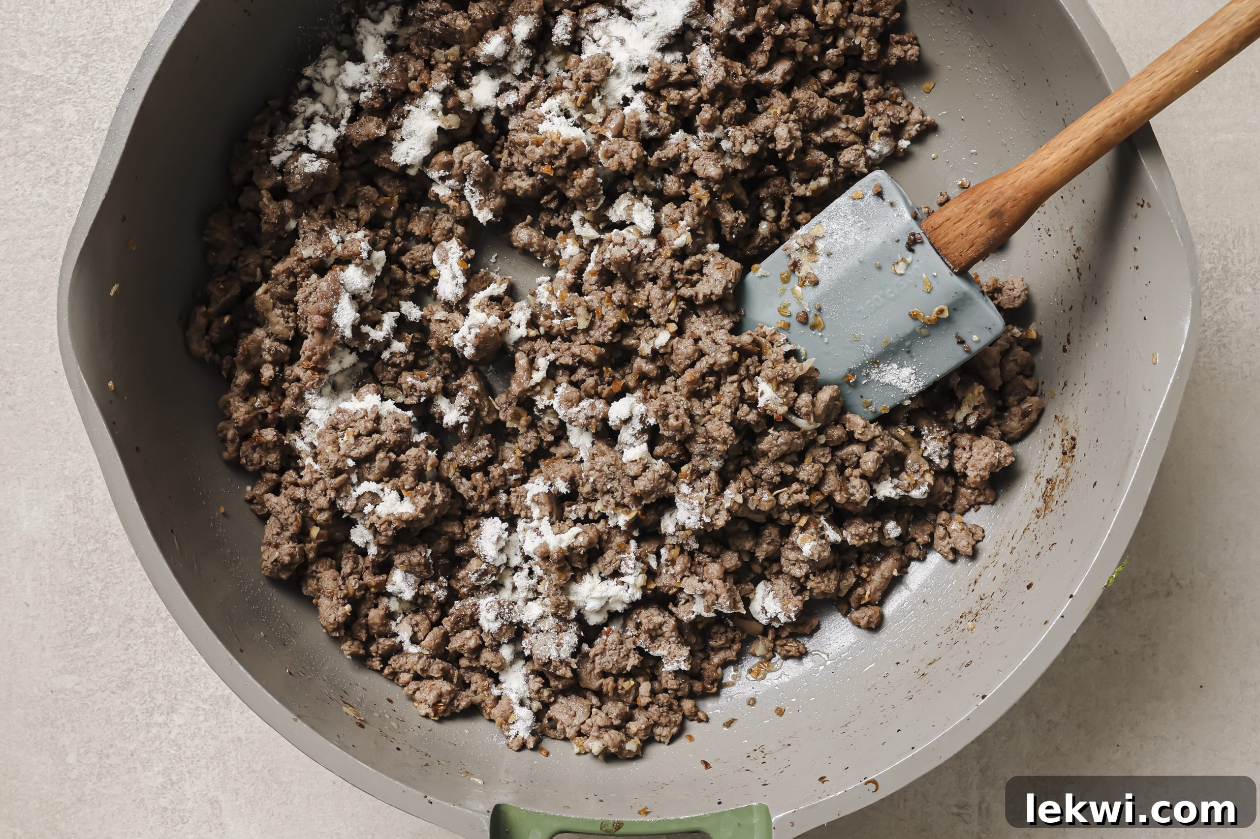 Arrowroot starch sprinkled evenly over the seasoned ground beef and aromatics in the pan.