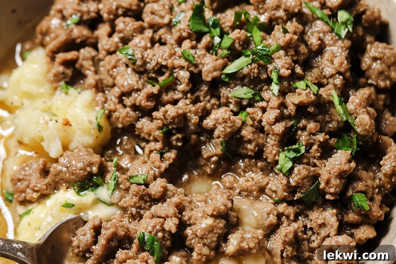 A bowl of delicious ground beef and gravy generously ladled over mashed potatoes, ready to be served.