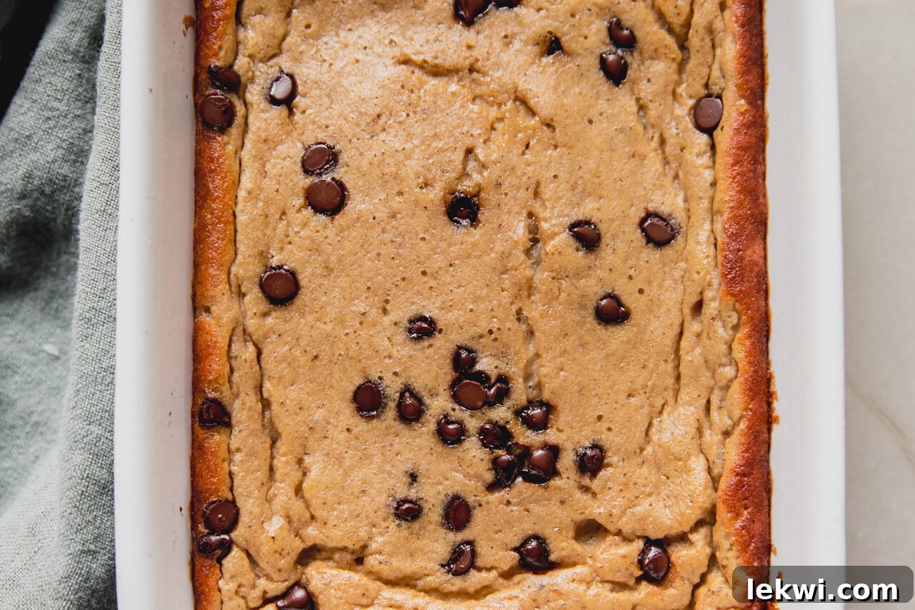 The freshly baked banana protein breakfast cake, golden brown and risen, is shown in the baking dish before it has been sliced.