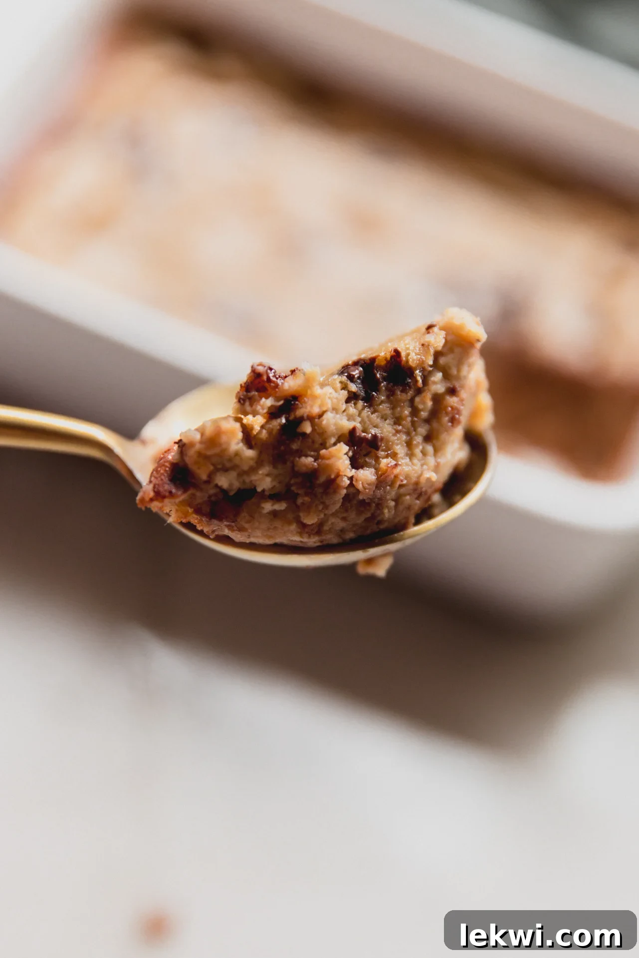 A close-up of a spoonful of Banana Protein Breakfast Cake, showing its moist texture and chocolate chips, poised to be enjoyed.