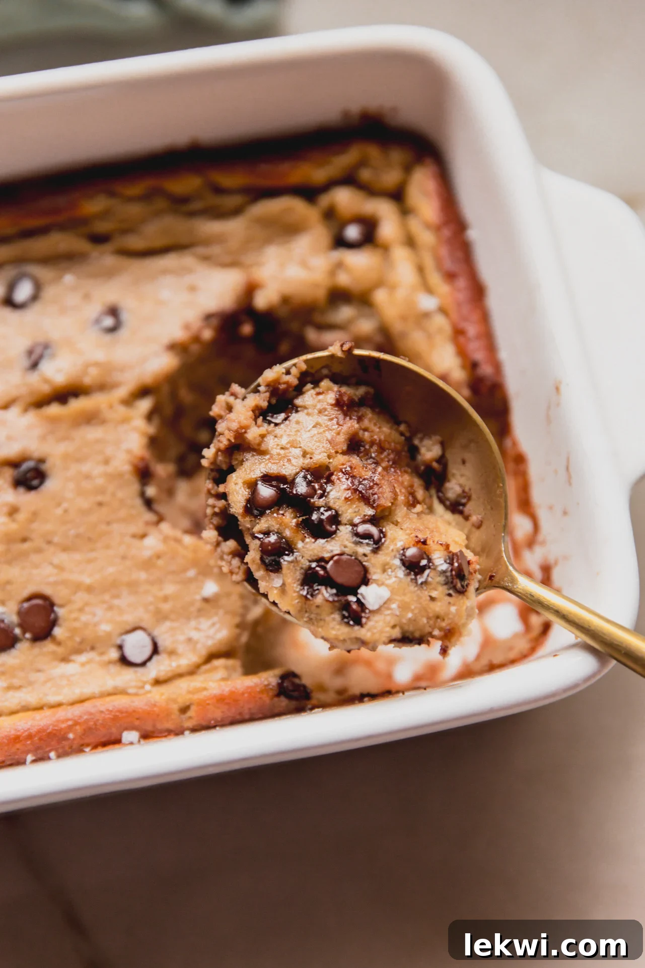 Banana protein breakfast cake being scooped with a spoon from a small baking dish.