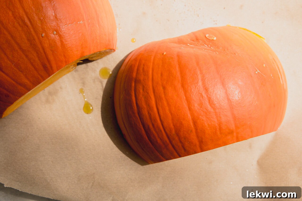 The seasoned sugar pumpkin halves placed face-down on a baking sheet lined with parchment paper.