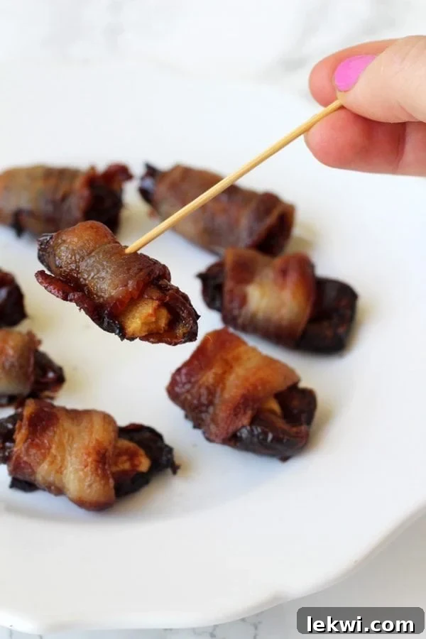 A plate with bacon wrapped dates and with a tooth pick picking one of them up.