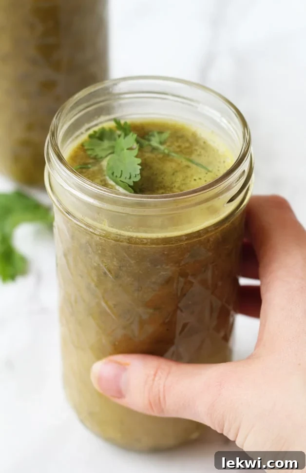 A glass mug of bone broth green drink being held in a hand.