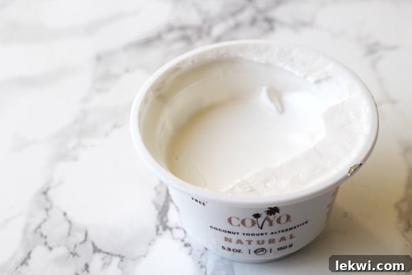 A container of Coyo Coconut yogurt with the top off sitting on a counter.