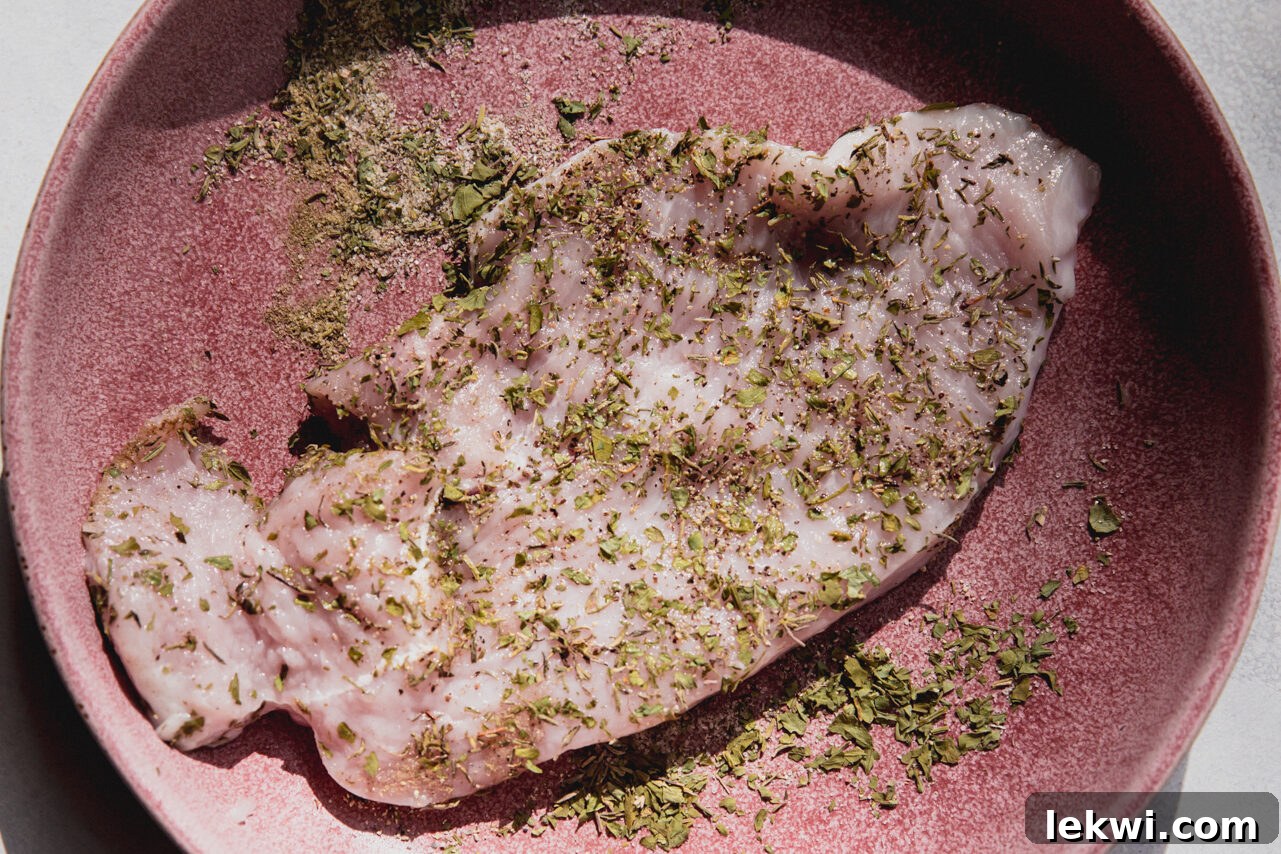 Raw turkey cutlets generously coated with a blend of dried herbs and spices, ready for cooking.
