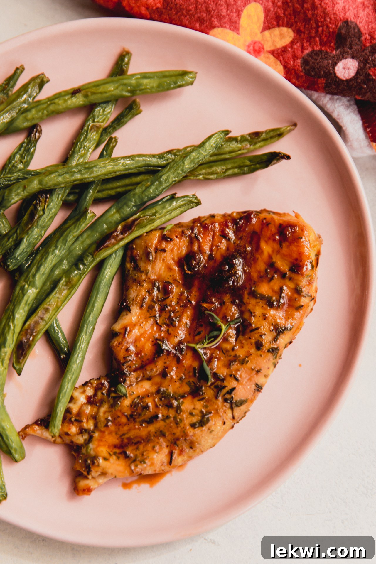 A plated orange-glazed turkey cutlet, garnished with fresh thyme, served alongside vibrant green beans and other healthy sides.