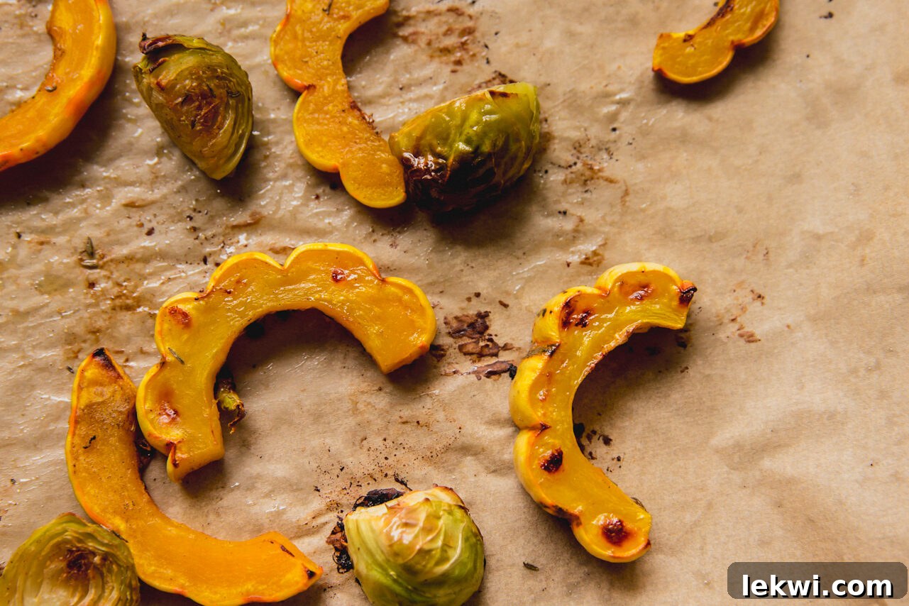 Roasted delicata squash and brussels sprouts, golden brown and caramelized after baking.
