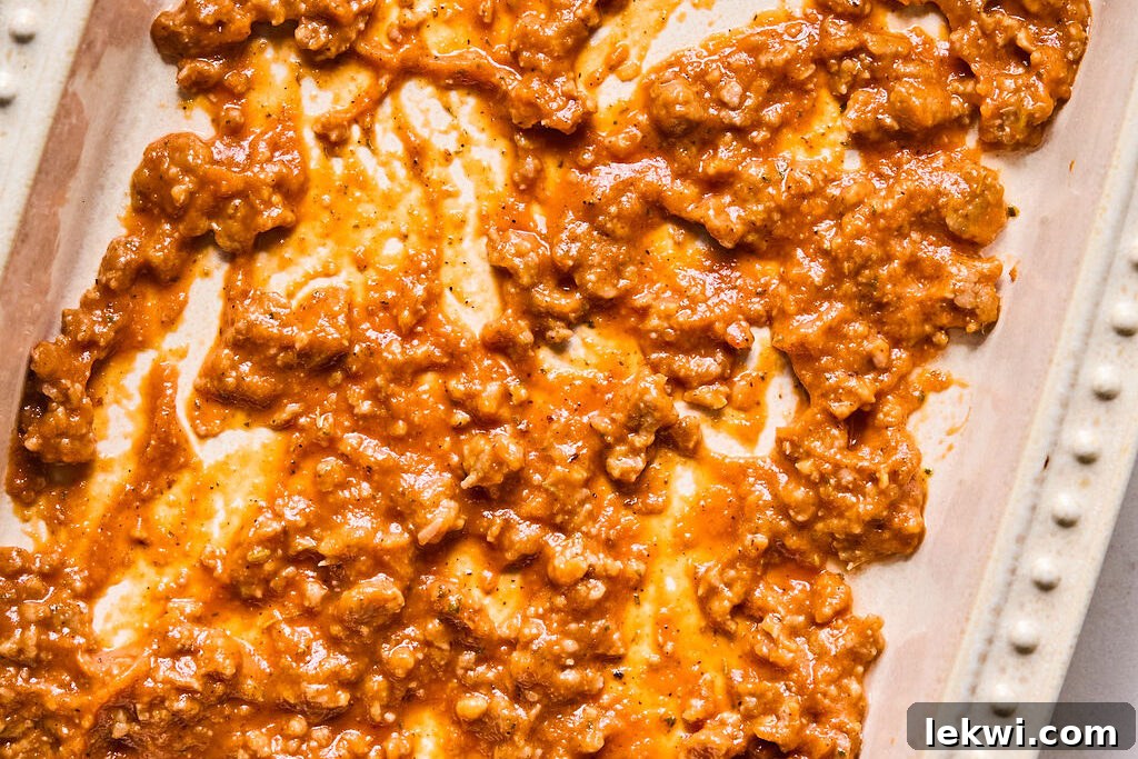 The bottom of a 9x13 inch casserole dish covered with a thin layer of butternut squash meat sauce.