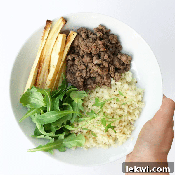 A bowl filled with ground beef, cauliflower rice, and roasted sweet potatoes.