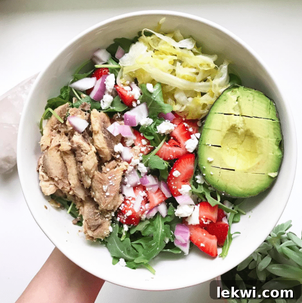 A bowl with a strawberry and avocado salad filling it.