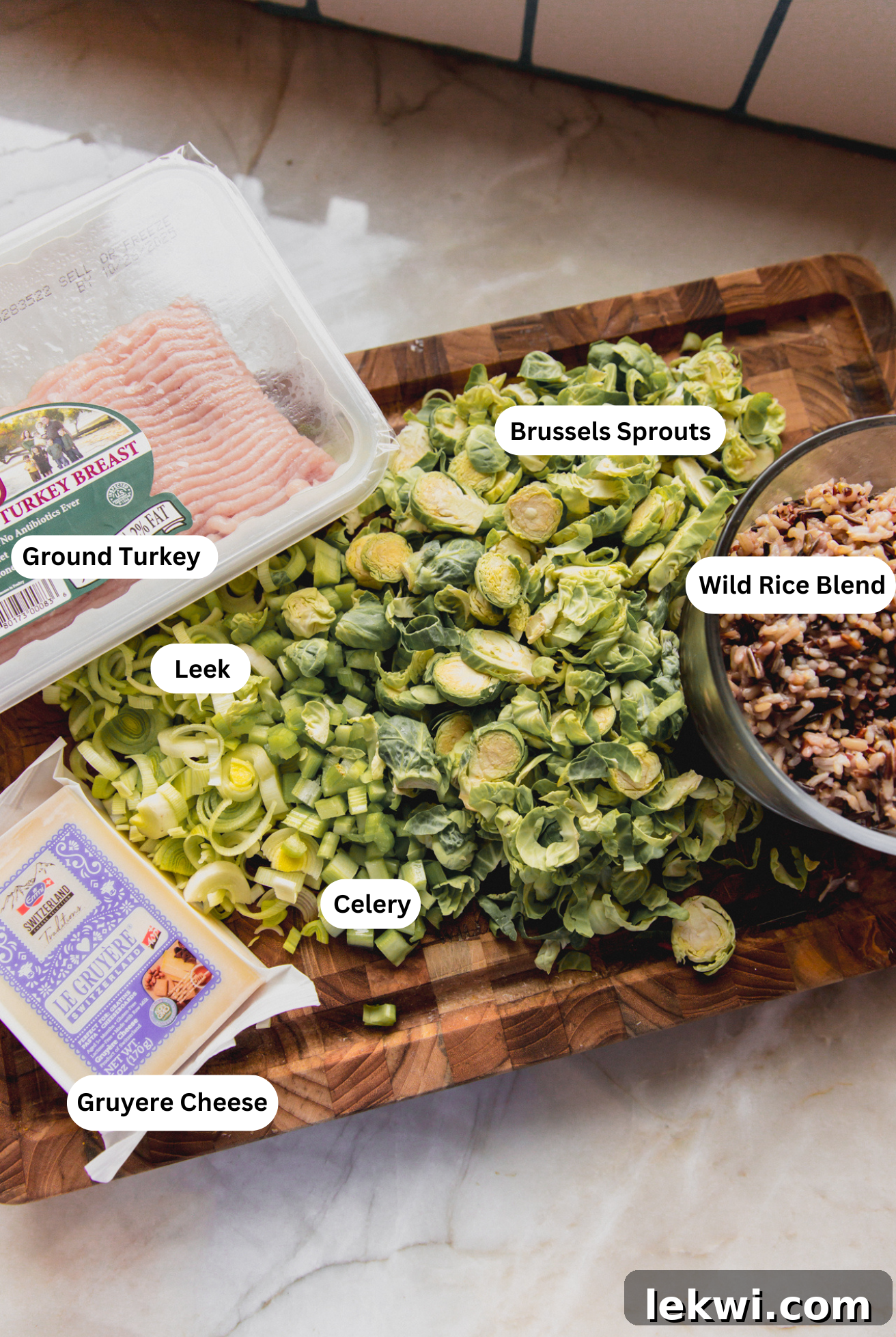 A vibrant display of ingredients for wild rice stuffed pumpkin laid out on a cutting board, including fresh pumpkin, ground turkey, and various vegetables.