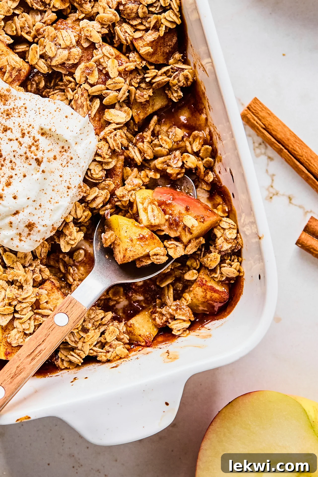 Protein apple crisp in a baking dish with a spoon taking a small serving.