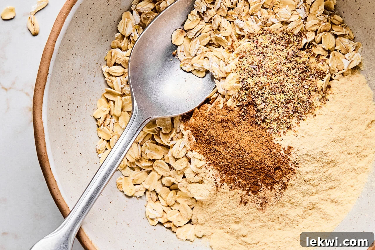 The oats, cinnamon, protein powder, and flax in a bowl with a spoon before mixing.