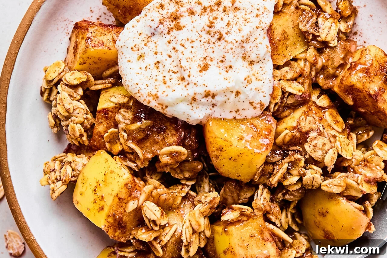 A serving of protein apple crisp on a plate topped with cinnamon and yogurt.