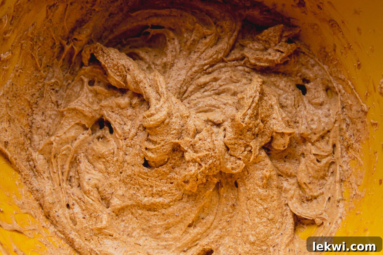 A yellow mixing bowl filled with rich, brown cookie dough after all ingredients have been thoroughly combined.