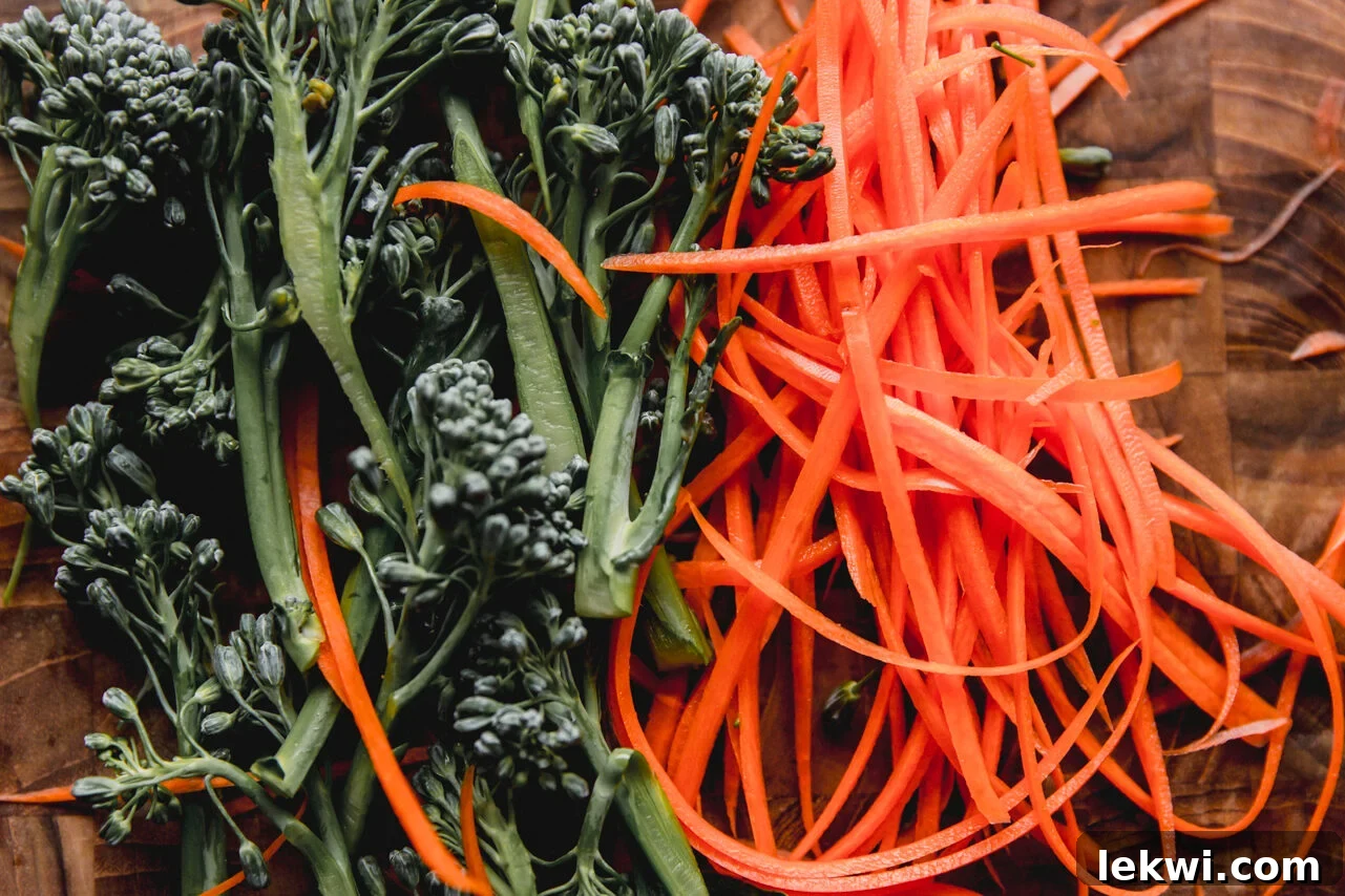 Fresh, vibrant broccoli and finely shredded carrots arranged on a cutting board, prepped and ready for cooking.