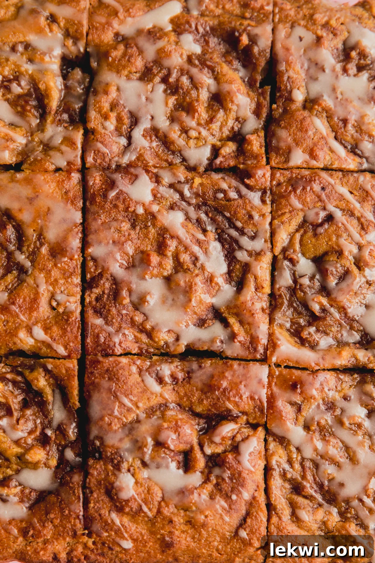 Gluten free cinnamon roll cake sliced into 9 slices and topped with a glaze icing.